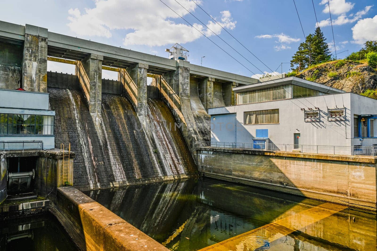 A dam on the Brno Reservoir by the Svratka River with a small power plant. Beautiful sunny summer day in nature.
