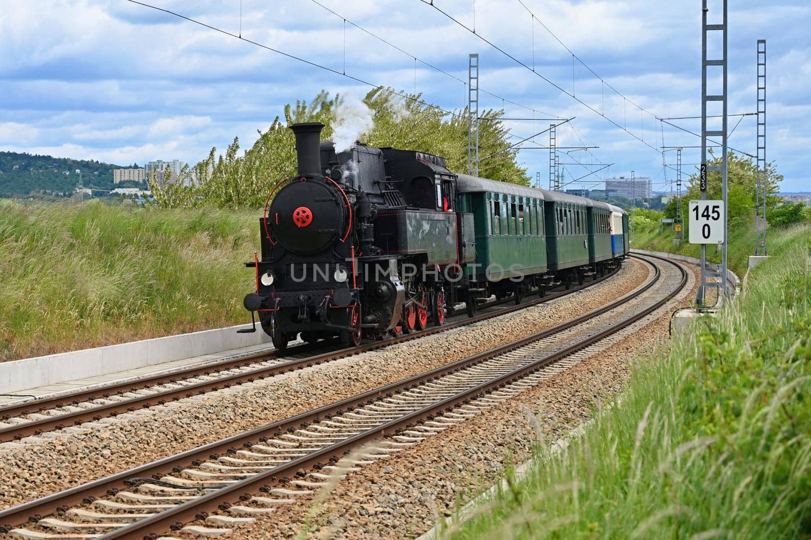 Old Czech historical steam train with wagons driving on the tracks for a trip. Concept for railways and history.