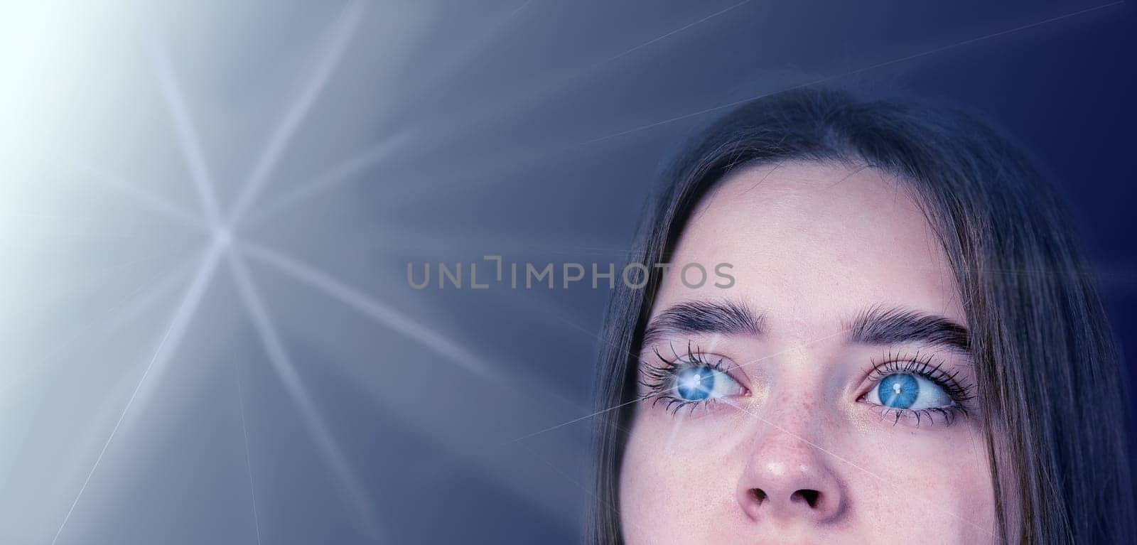 A young person with striking blue eyes looks up thoughtfully, illuminated by a gentle light that creates an ethereal atmosphere.