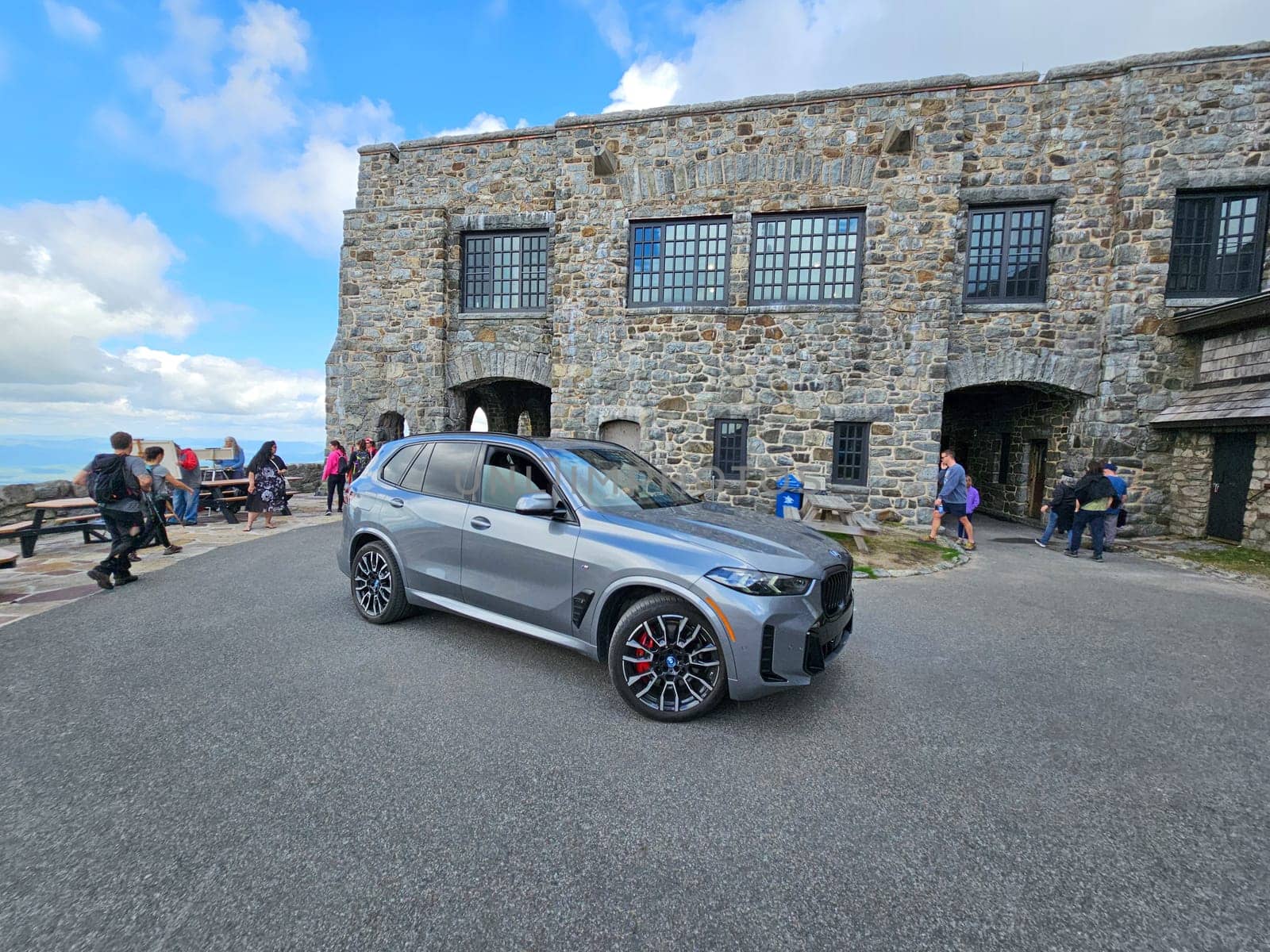 Wilmington, NY USA - 05.23.2024: Modern BMW X5 SUV at Scenic Overlook with Stone Building and Distant Landscape Views at Whiteface Mountain.