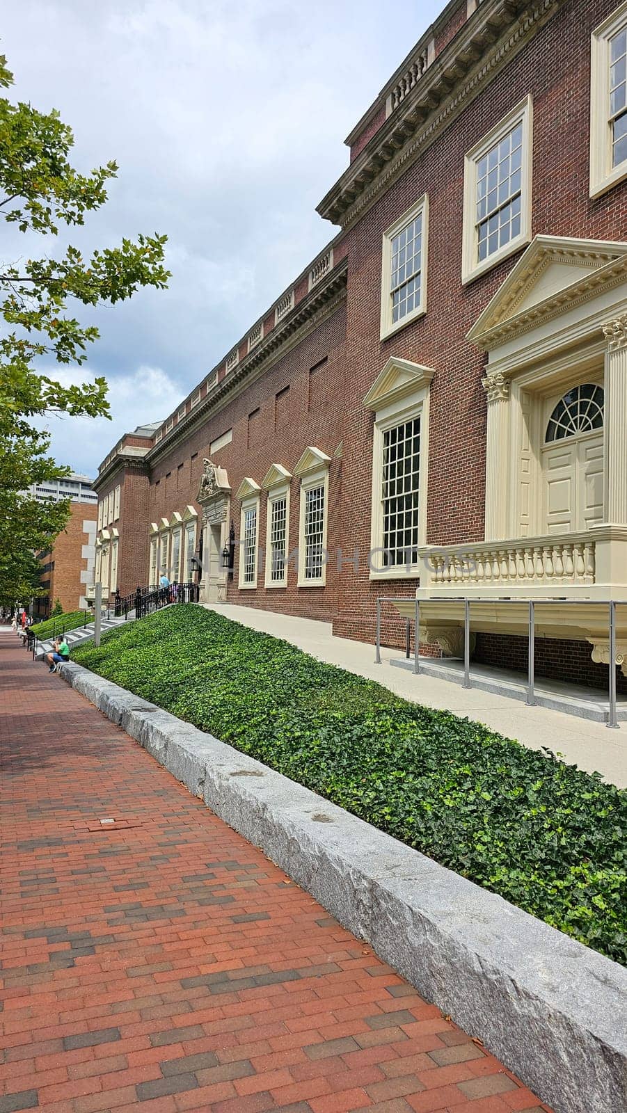 Boston, MA USA - 08.04.2024: Historical Brick Building Facade with Ivy Covered Hill in Urban Setting, New England Area.