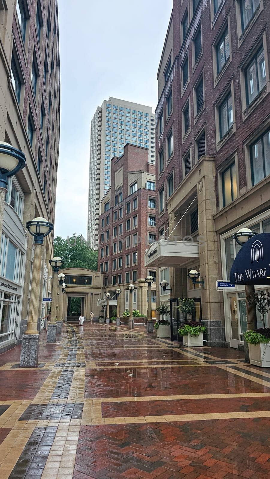 Boston, MA USA - 08.04.2024: Downtown Urban Landscape with Wet Brick Pavement and Towering Buildings on a Rainy Day.
