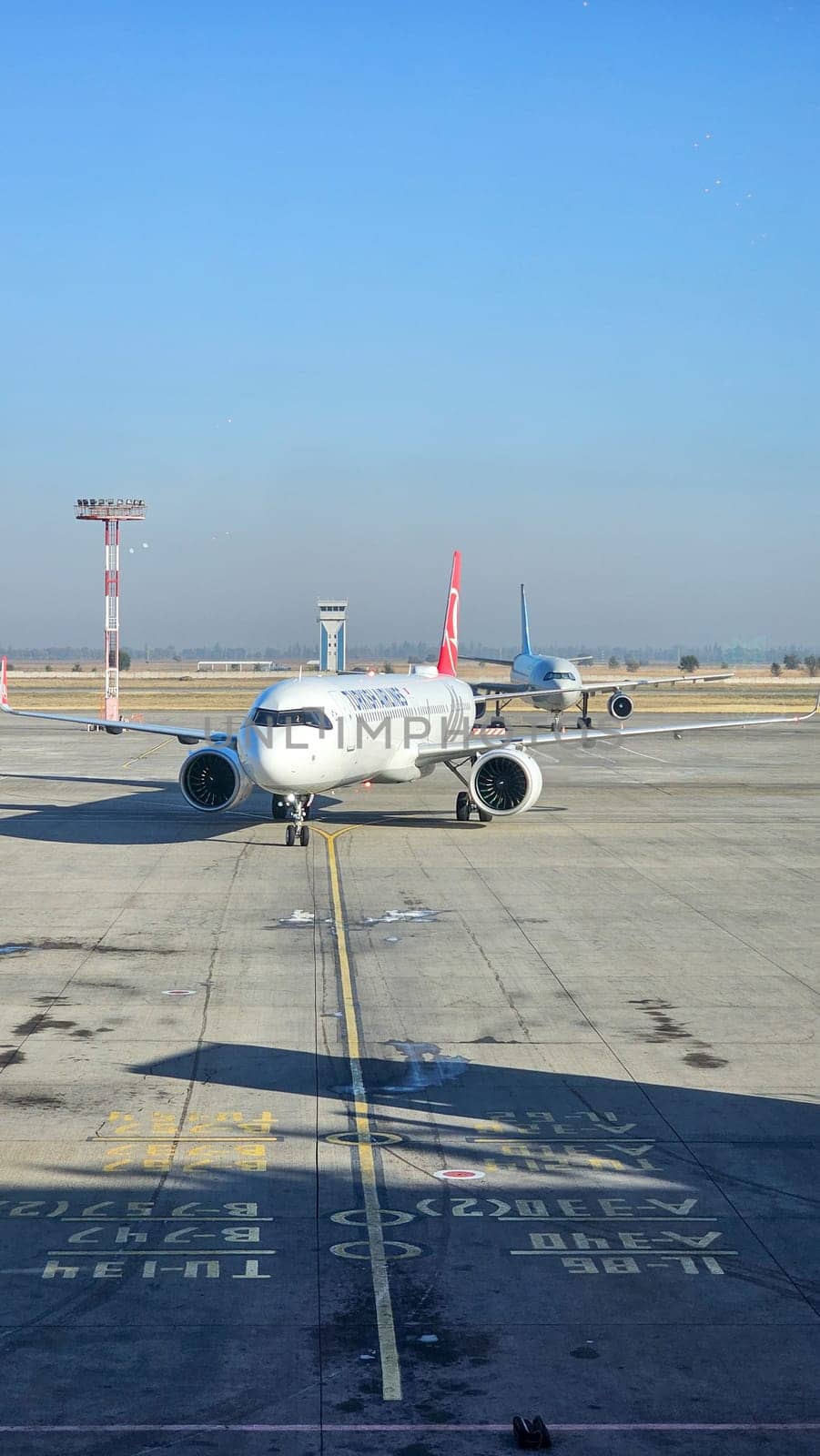 Bishkek, Kyrgyzstan - 10.09.2024: Wide Angle View of a Commercial Turkish Airplane Parked on the Airport Runway, Readying for Takeoff.