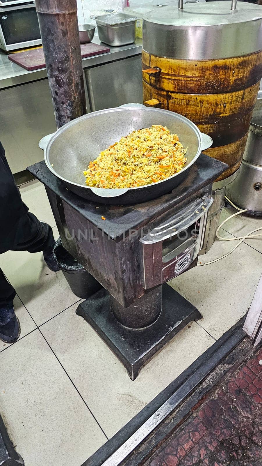 Bishkek, Kyrgyzstan - 10.05.2024: Hearty Asian Pilaf Simmering in a Traditional Cauldron on a Wood-Fired Stove.