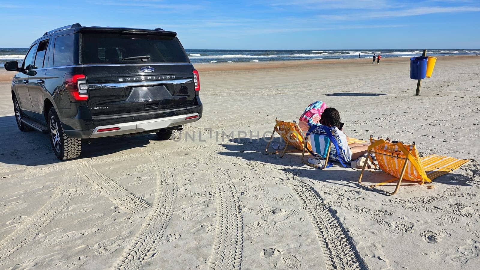 Daytona Beach, FL USA - 01.01.2025: SUV on Beach with People Relaxing Coastal Getaway Scene with Vehicle and Beachgoers.