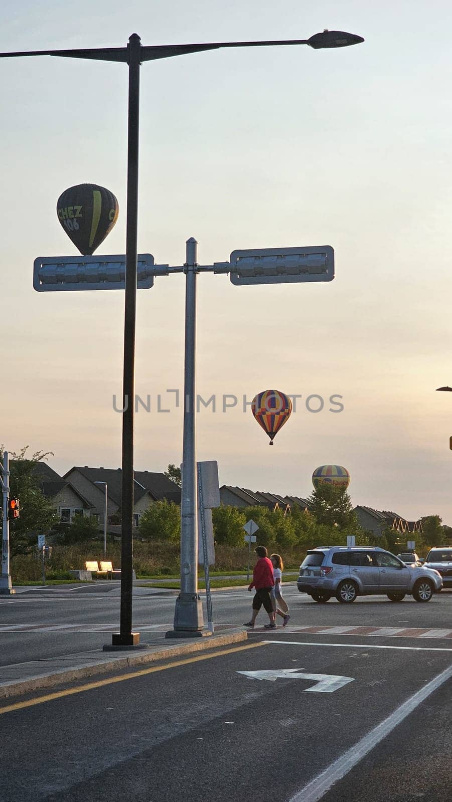 Gatineau, QC Canada - 08.29.2024: Scenic Urban Intersection with Hot Air Balloons at Sunset People, Car, and Cityscape.