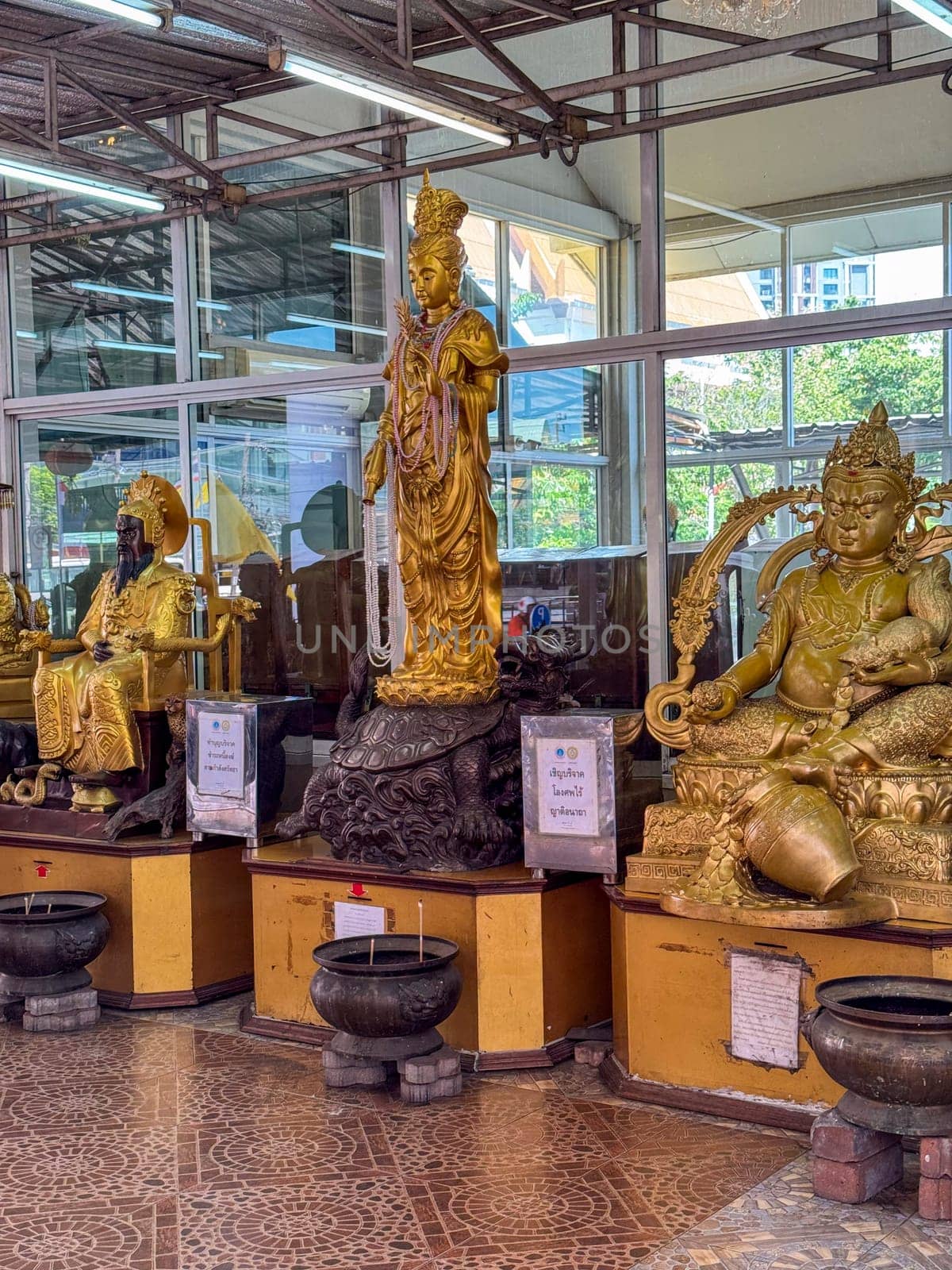 Bangkok, Thailand - November 11, 2024: Majestic spirit house with golden details and garlands, standing as a religious monument in Bangkok, showcasing Thai culture, faith and spiritual devotion.