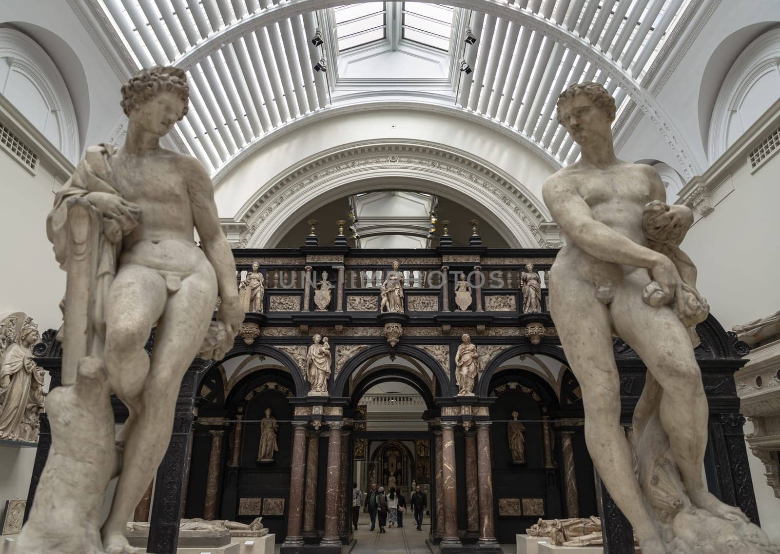 London, UK - May 07, 2025 - 16th century marble sculptures of Apollo and Zephyr by Francavilla with The pulpitum from St. John's Cathedral (s-Hertogenbosch) in the background, displayed inside Exhibition hall of The Victoria and Albert Museum in London, use it as your Wallpaper, Poster and Space for text, Selective focus.