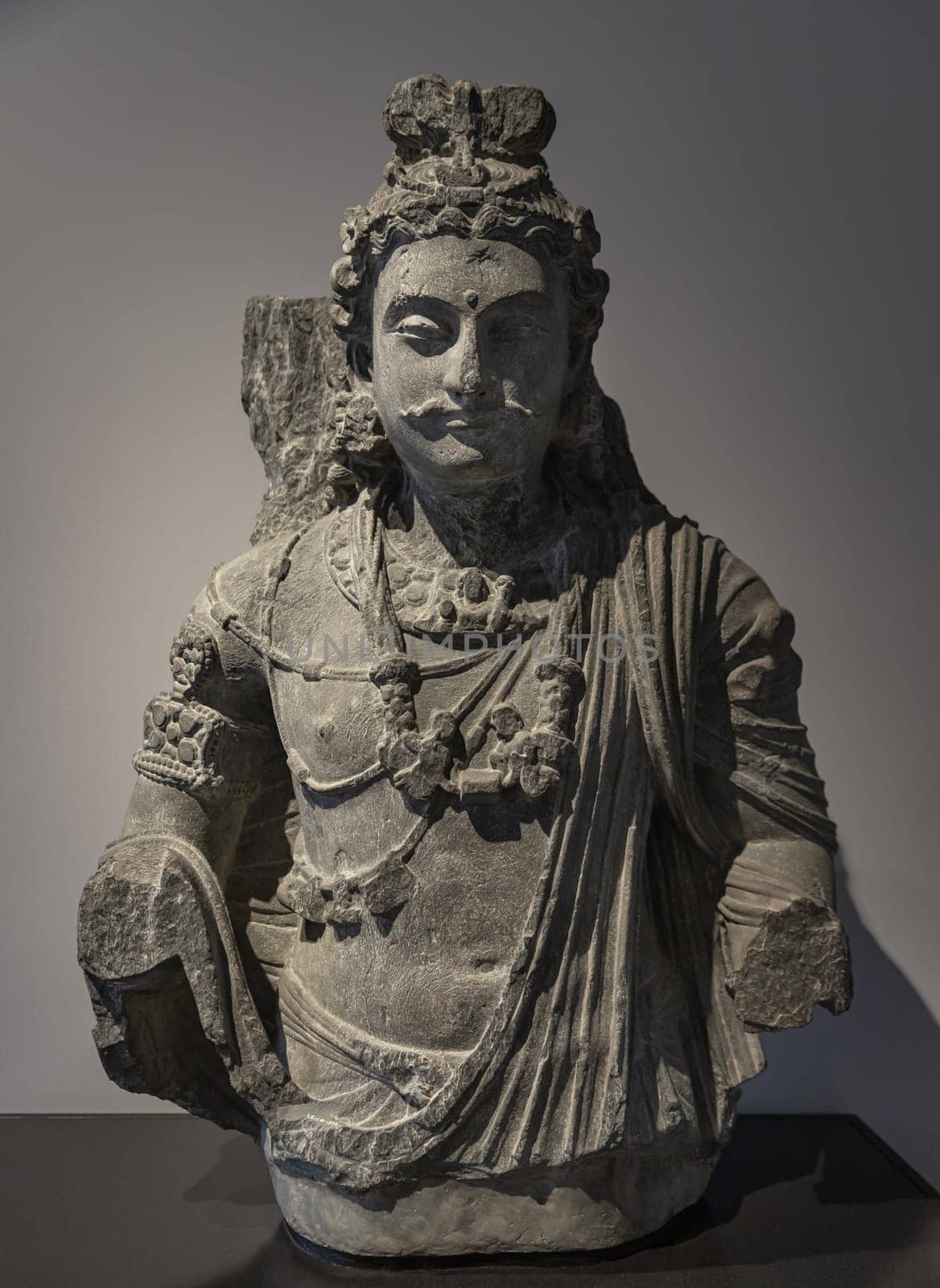 London, UK - May 07, 2025 - Bust of a Bodhisattva Maitreya Sculpture (Sanskrit) or Metteyya (Pali) displayed in The V&A (Victoria and Albert Museum), is a central figure in Mahayana Buddhism and in Tibetan Buddhism he is known as the "Lord of Love" or the "Noble Loving One" (Pakpa Jampa), and his name means "friendliness" or "loving-kindness". use it as your Wallpaper, Poster and Space for text, Selective focus.
