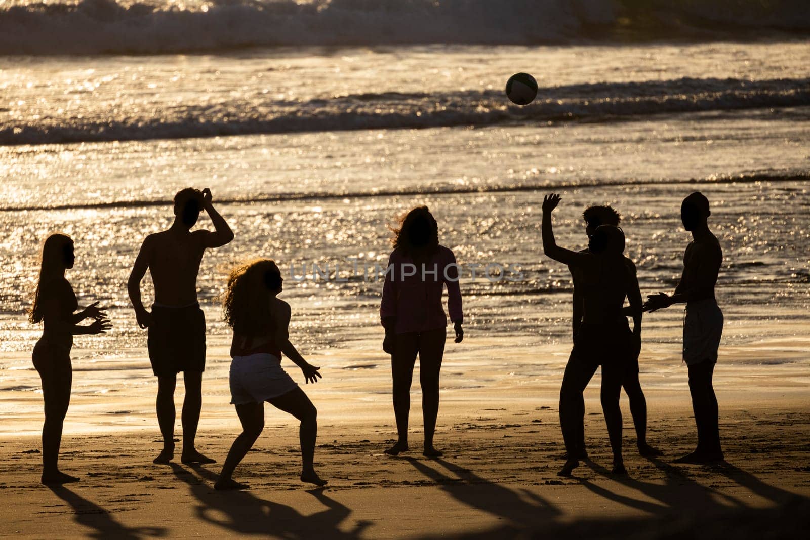 Silhouetted friends enjoy a beach volleyball game at sunset, creating lasting memories