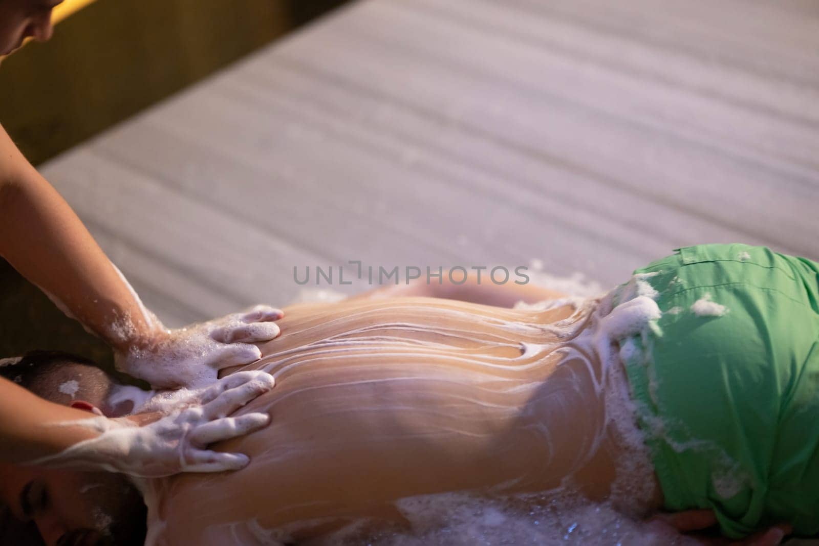 Back Massage with Foam. Therapist applies soap foam with htheir ands on patients back during traditional bath ritual