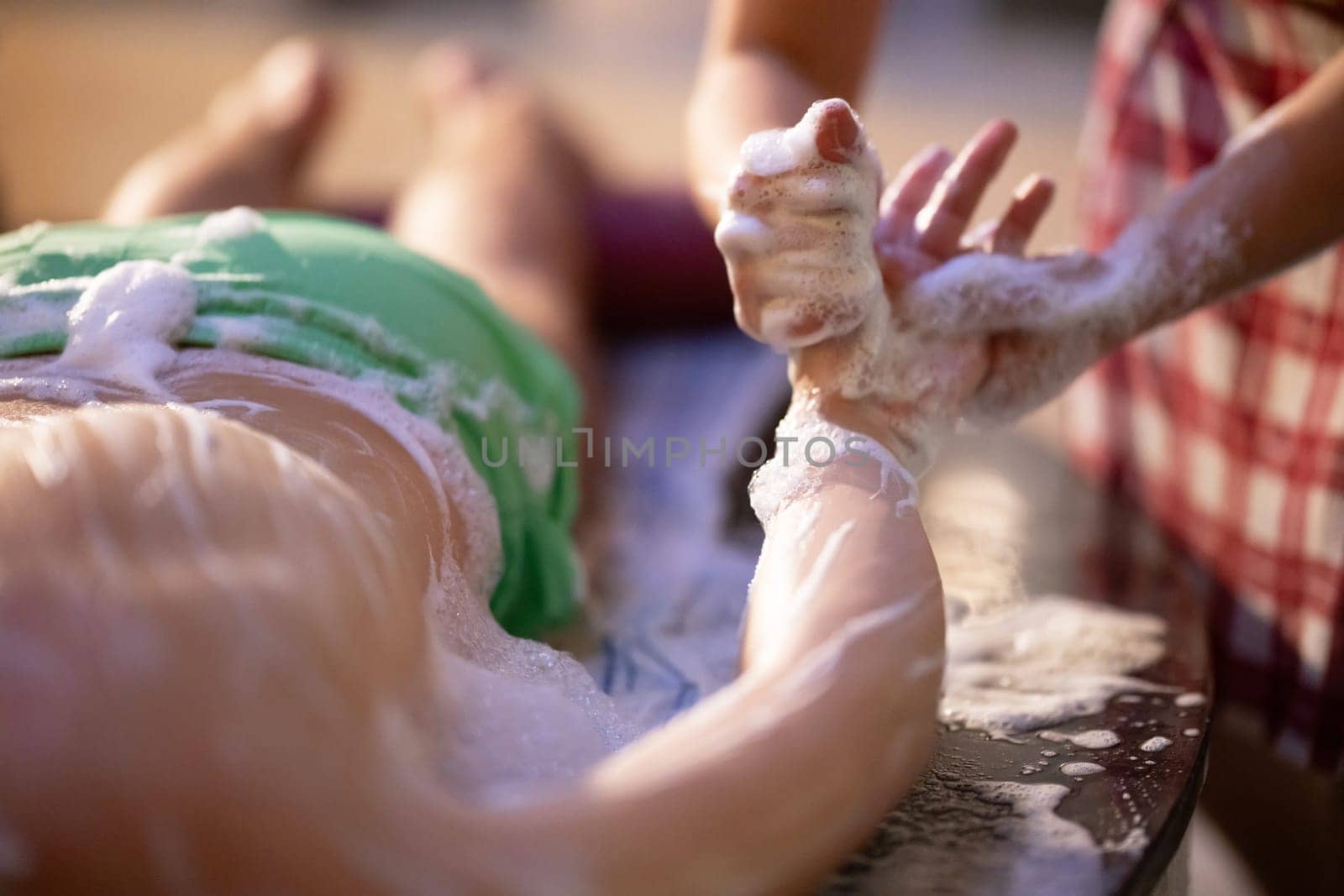 Hand Foam Therapy. Attendant gently washing patient hands with foamy soap in a traditional bath setting