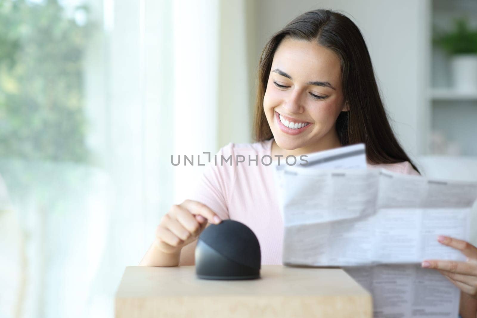 Happy woman learning to use a smart speaker reading manual