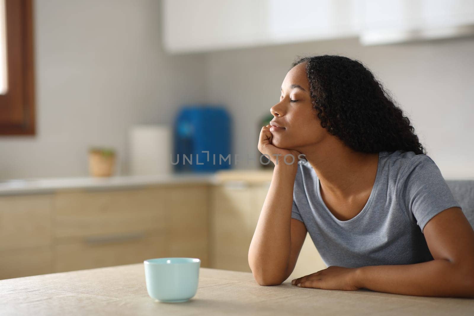 Black woman is relaxing sitting in a kitchen at home