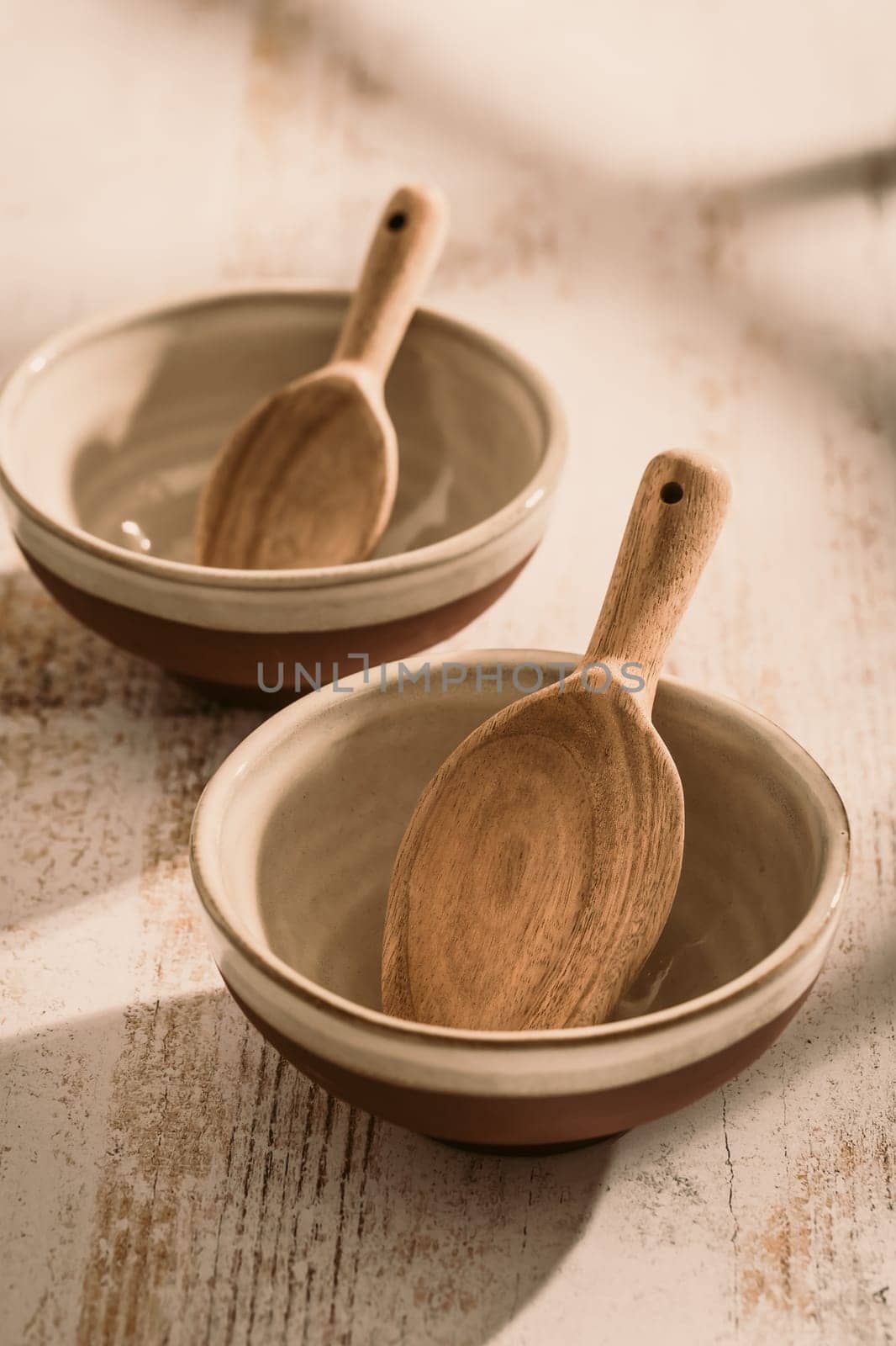 Two stoneware bowls with wooden spoon on kitchen table