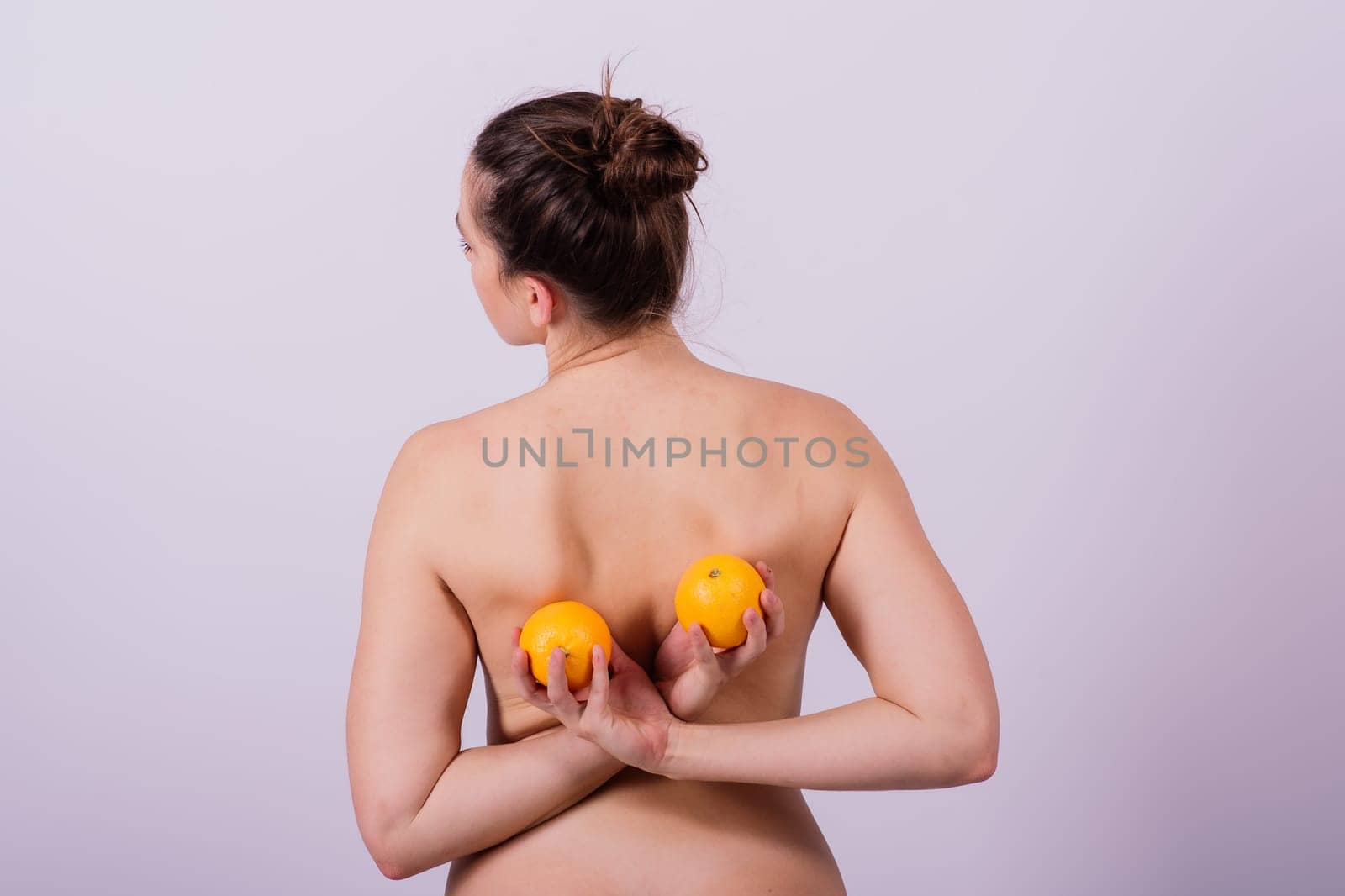Naked woman back with an orange fruit an isolated image