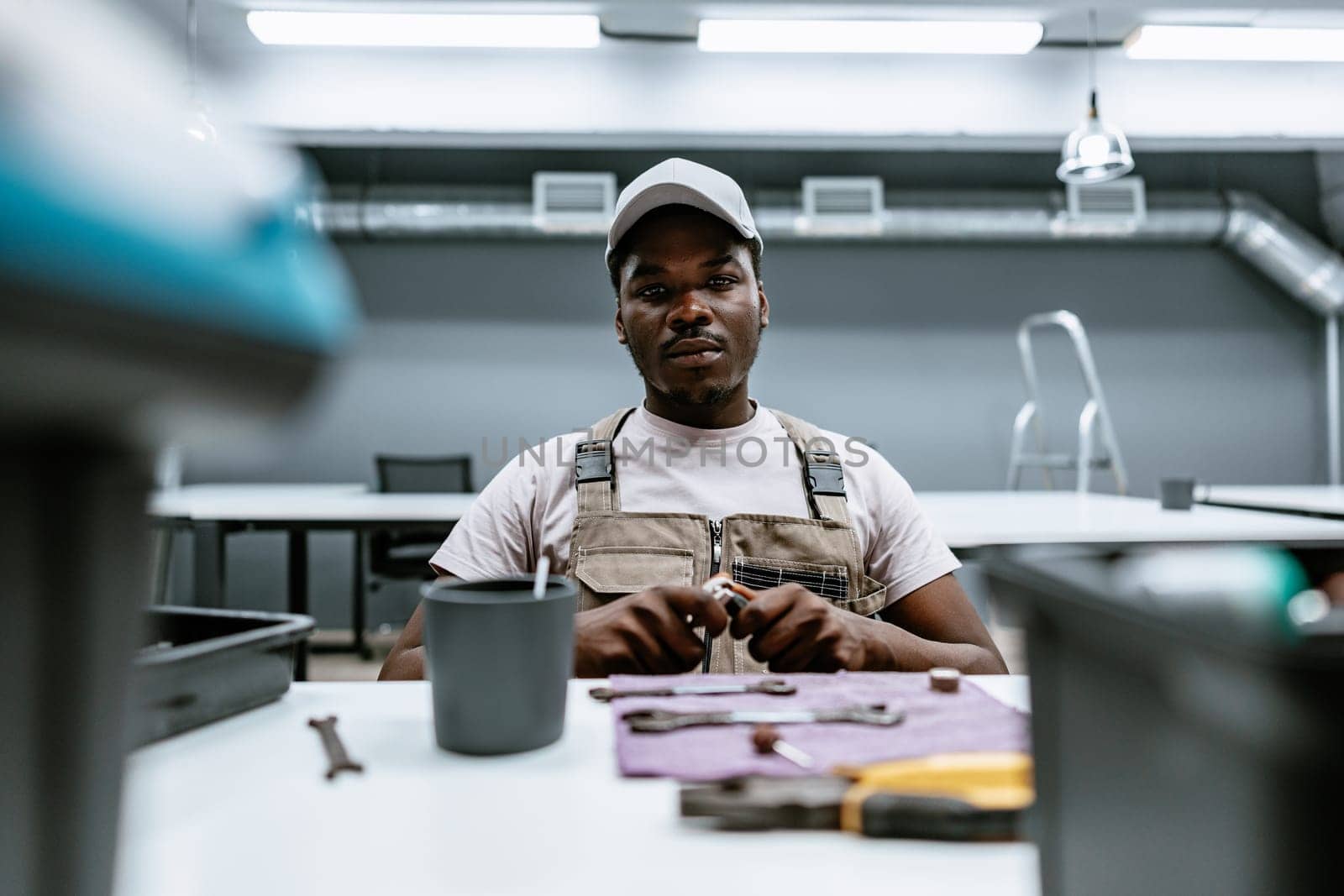 A technician is seated at a workstation in a contemporary workshop, meticulously assembling tools and parts, showcasing concentration and craftsmanship during daylight hours.