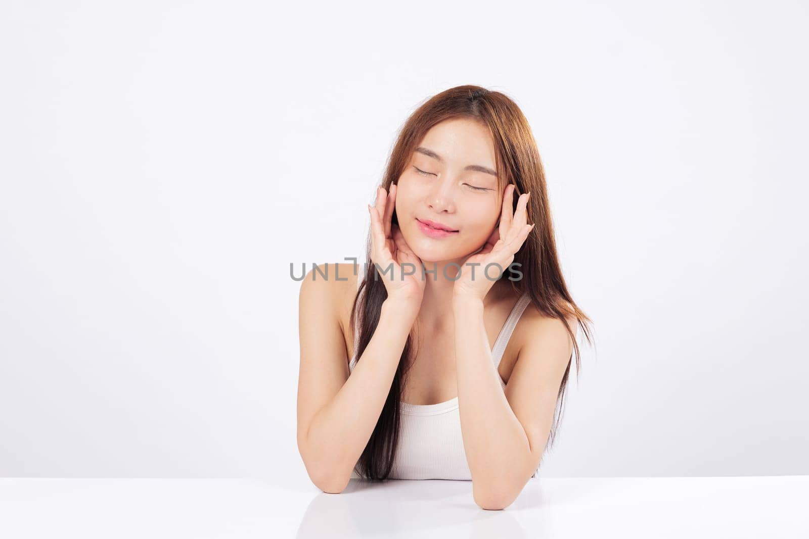 Skin brightness and healthy skin are beautifully displayed as Asian woman gently touches her face, showing elegance, softness, calm satisfaction of complete skincare routine. isolated white background