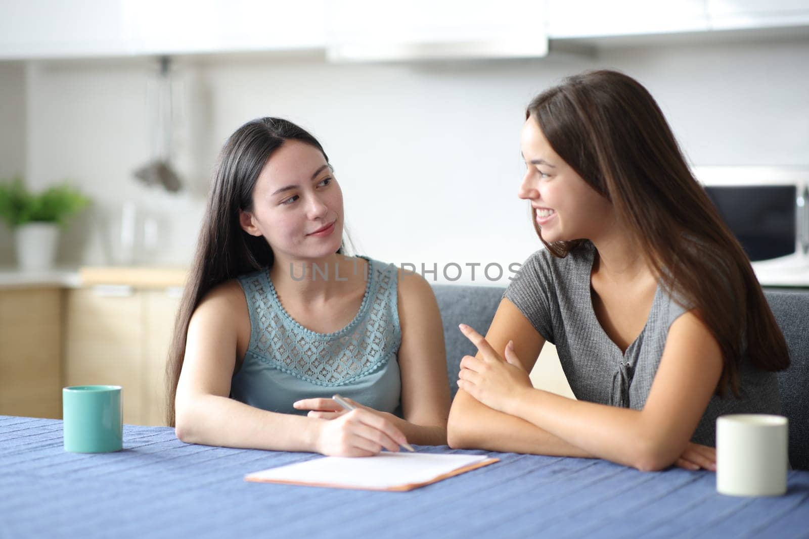 Interracial roommates talking about contract in the kitchen at home