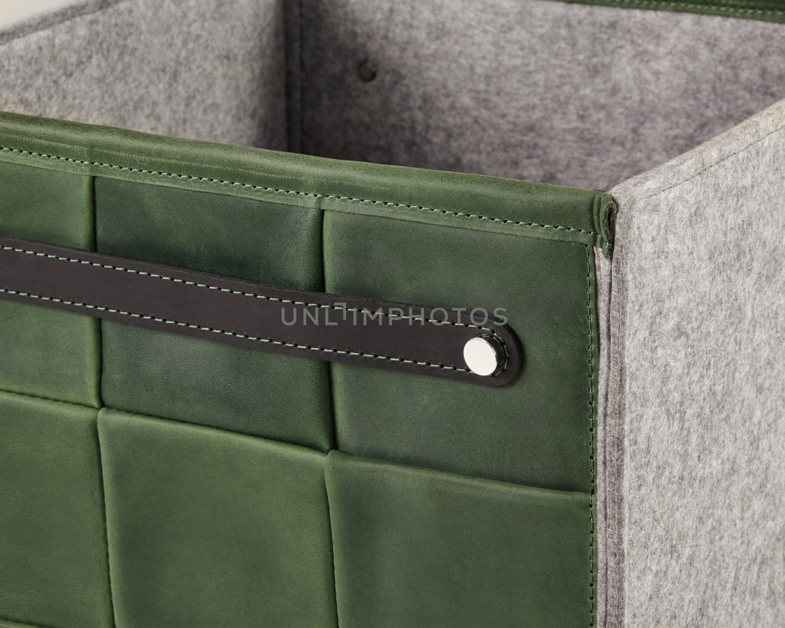 Close-up of a stylish green leather storage box featuring a gray felt lining and a sturdy leather handle