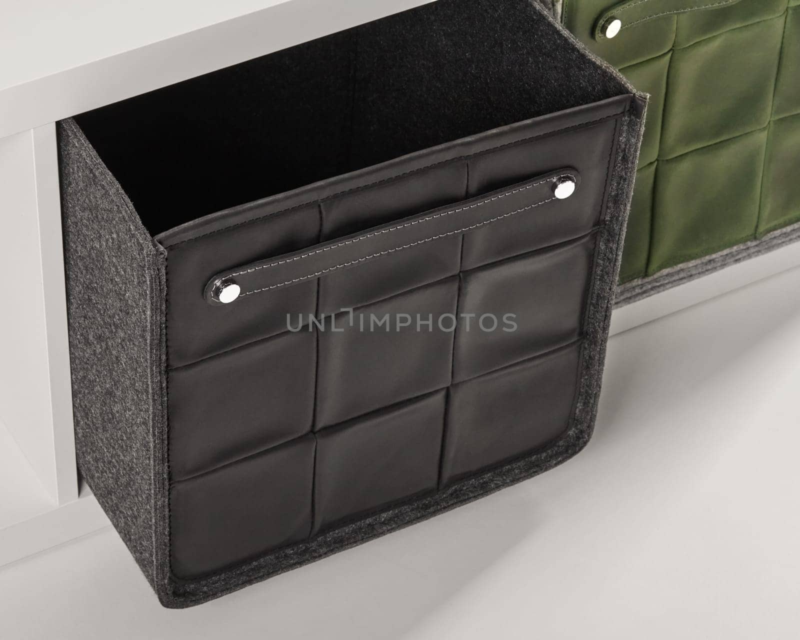Stylish black leather storage box with handle being pulled out of a white drawer