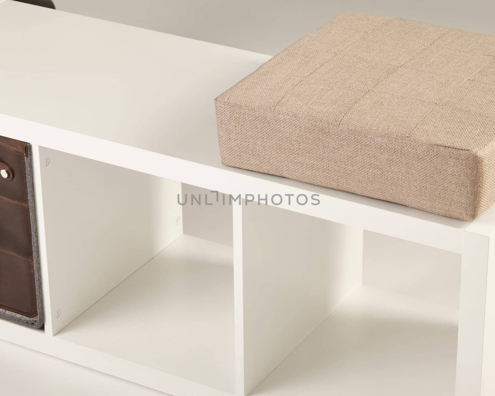 Stylish white storage bench featuring a comfortable beige cushion and empty compartments, perfect for organizing any living space