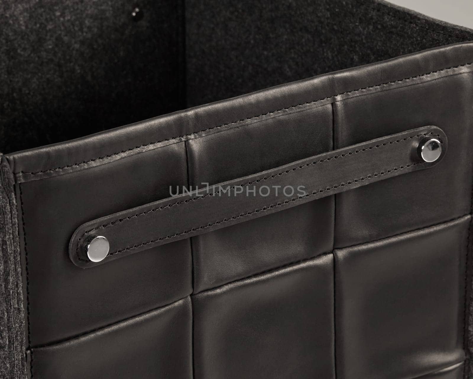 Close-up of a stylish black leather storage box featuring a felt lining and a sturdy metal handle