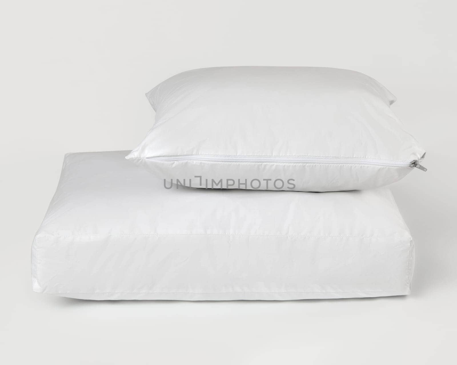 Clean white waterproof pillow and mattress protector on a white background, promoting hygiene and comfort