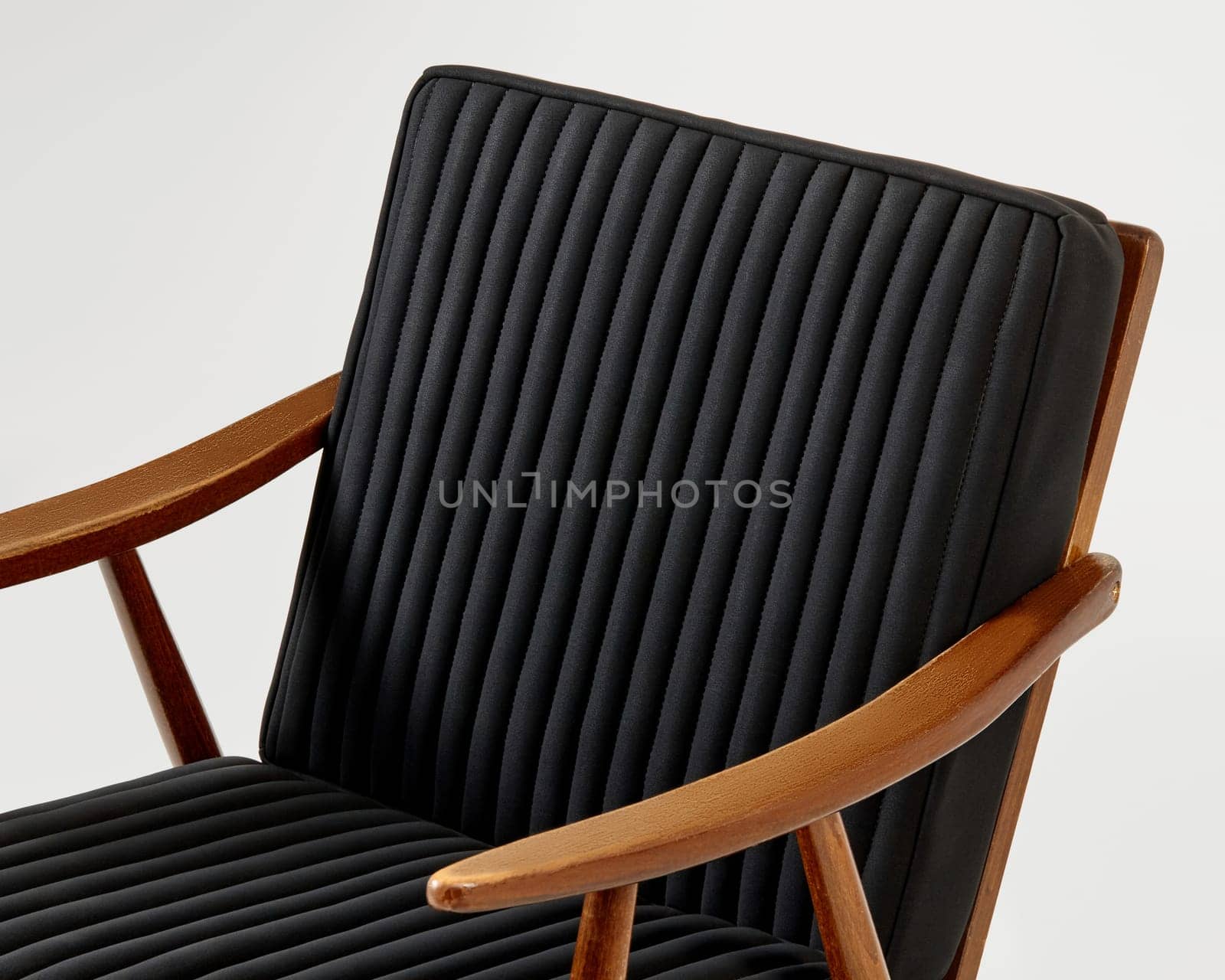 Comfortable black lounge chair with vertical channel tufting and light brown wooden frame, representing modern furniture design