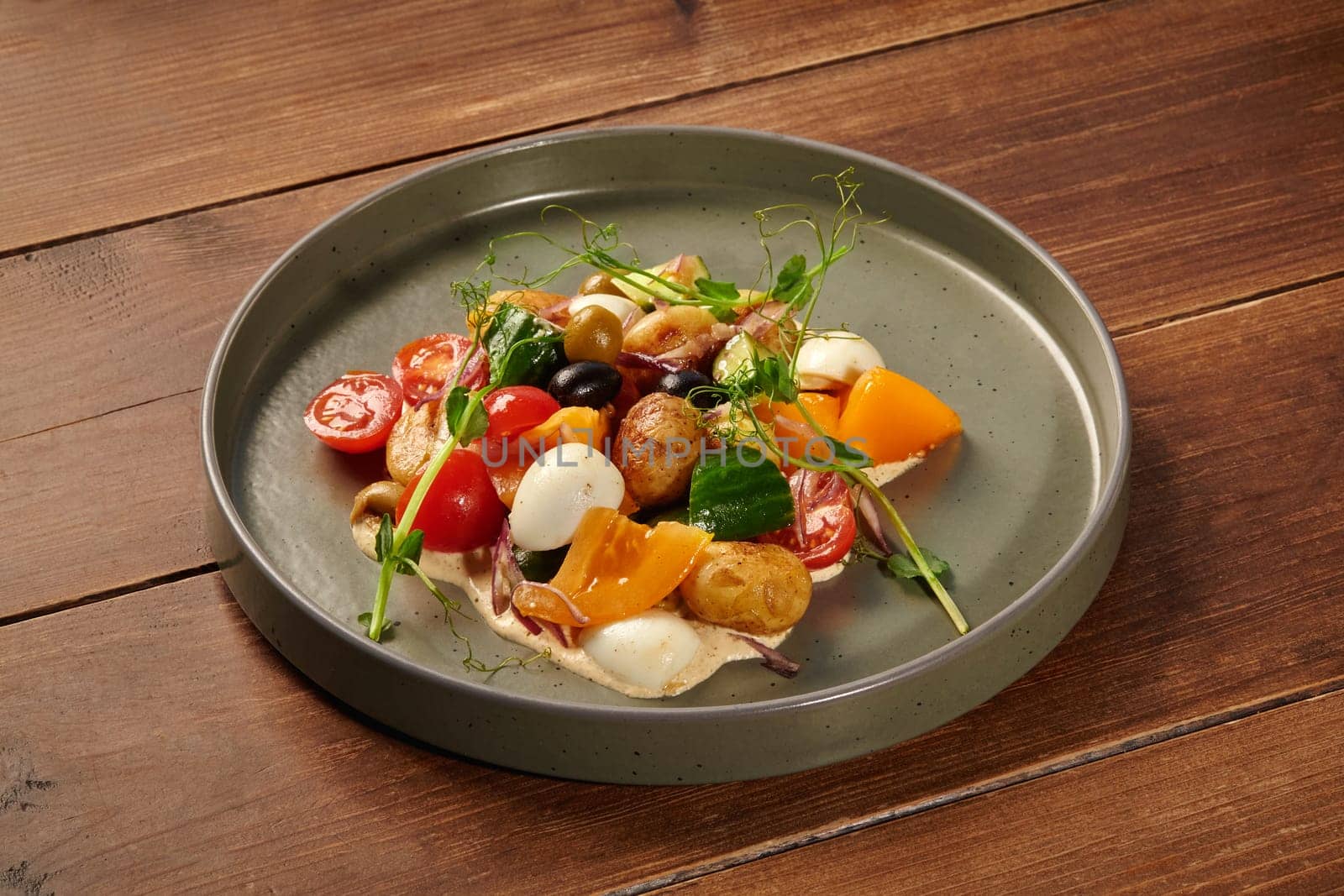 Fresh and vibrant mediterranean salad beautifully presented on a grey plate, featuring a mix of colorful vegetables and quail eggs