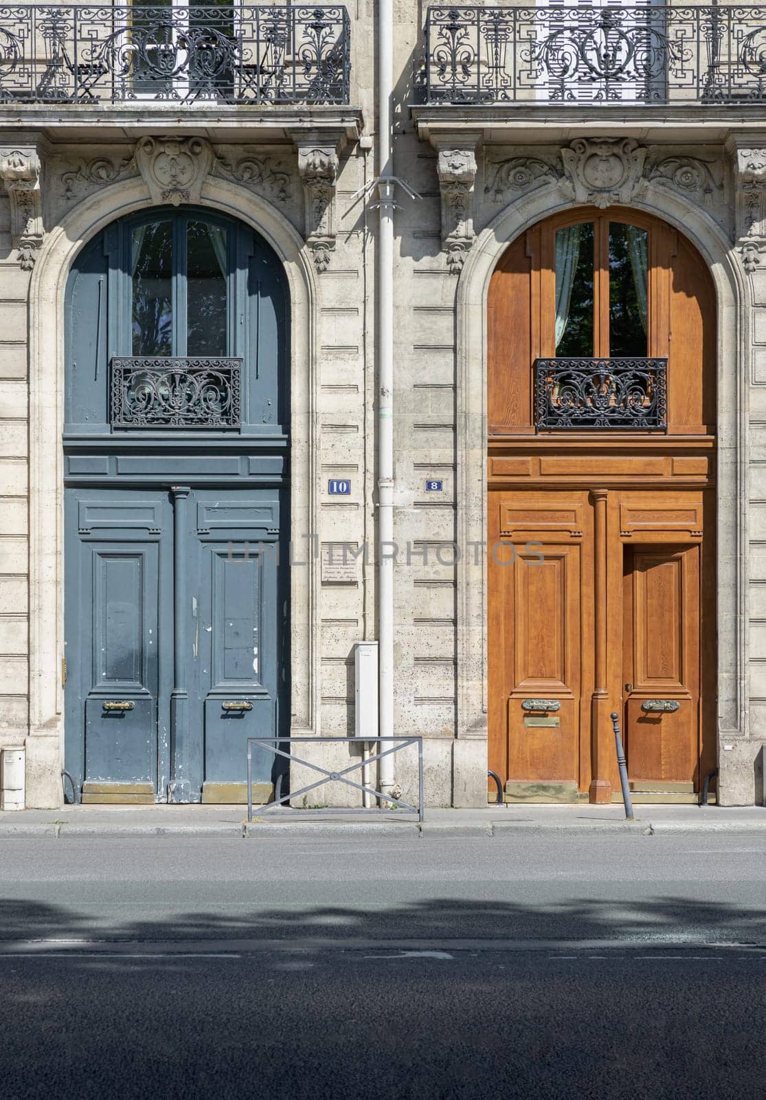 France, Paris - May 03, 2025 - Magnificent entrance facade doors of Ancient building in Paris. Architectural splendour details of wooden front doors with glass windows and wrought iron steel balcony, use it as your Wallpaper, Poster and Space for text, Selective focus.