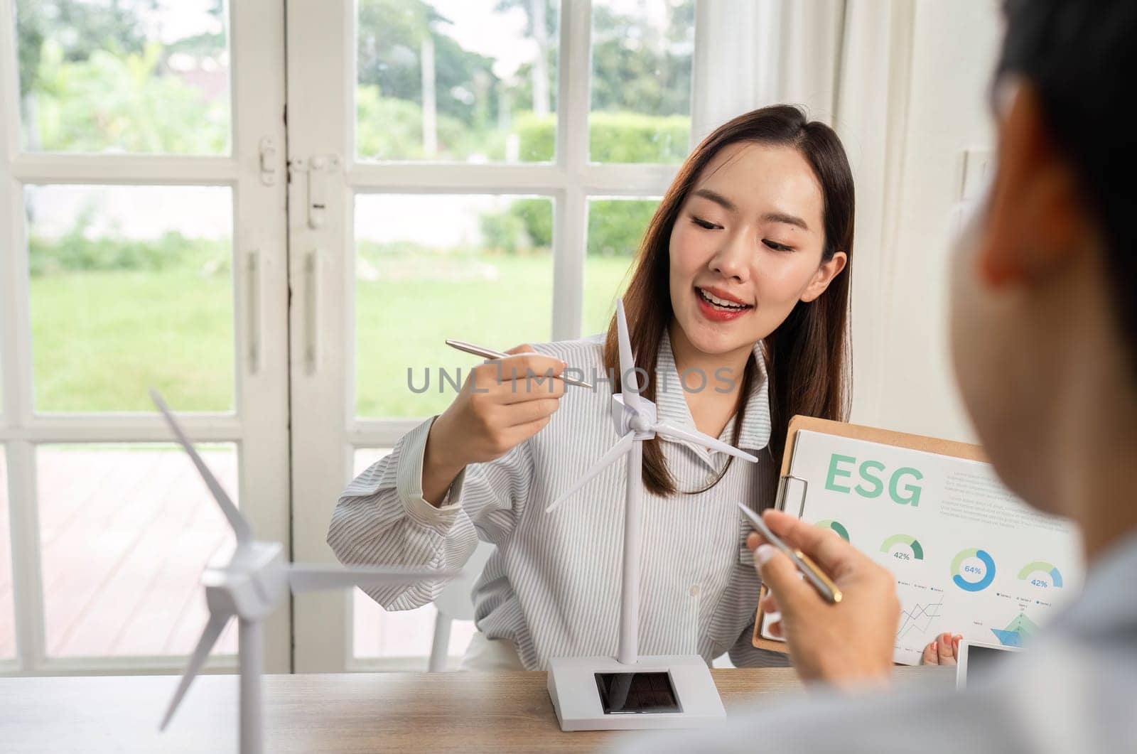 Two professionals engage in a discussion about ESG strategies, showcasing renewable energy models and data insights.