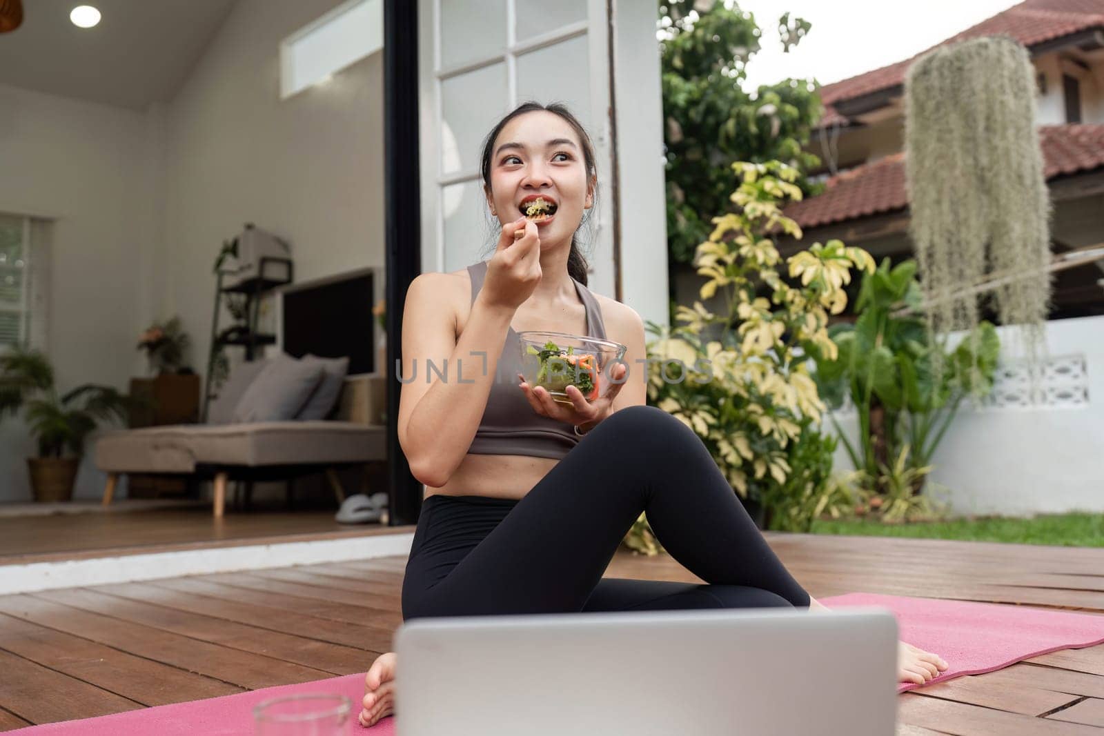A woman enjoying a fresh salad after a yoga session, embodying a lifestyle of health and mindfulness in her home.