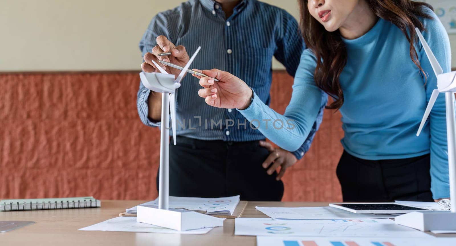 A woman and a man collaborate on a wind energy project, discussing model details and innovative solutions.
