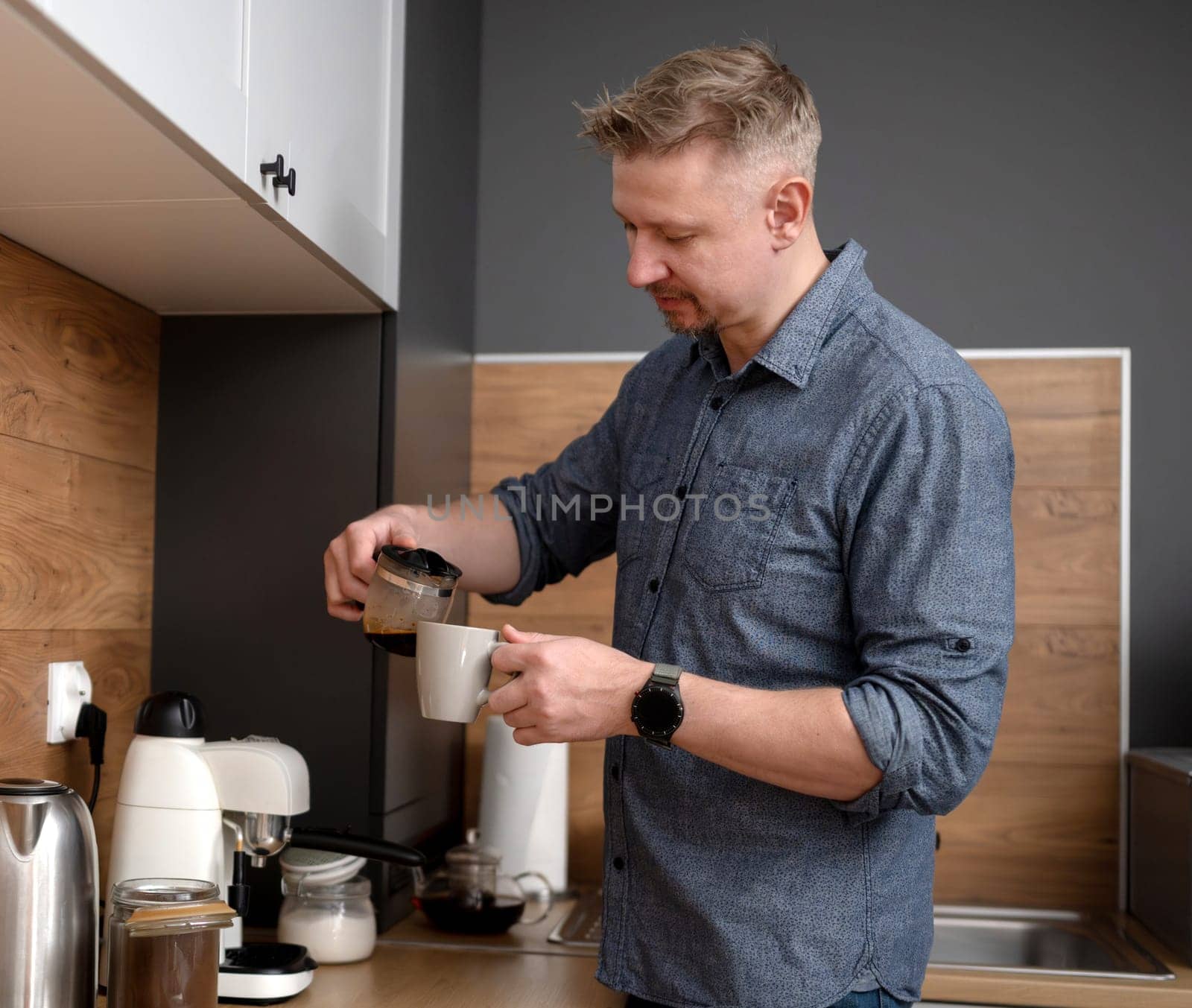 Handsome Man Pouring Himself Coffee At Home In The Kitchen