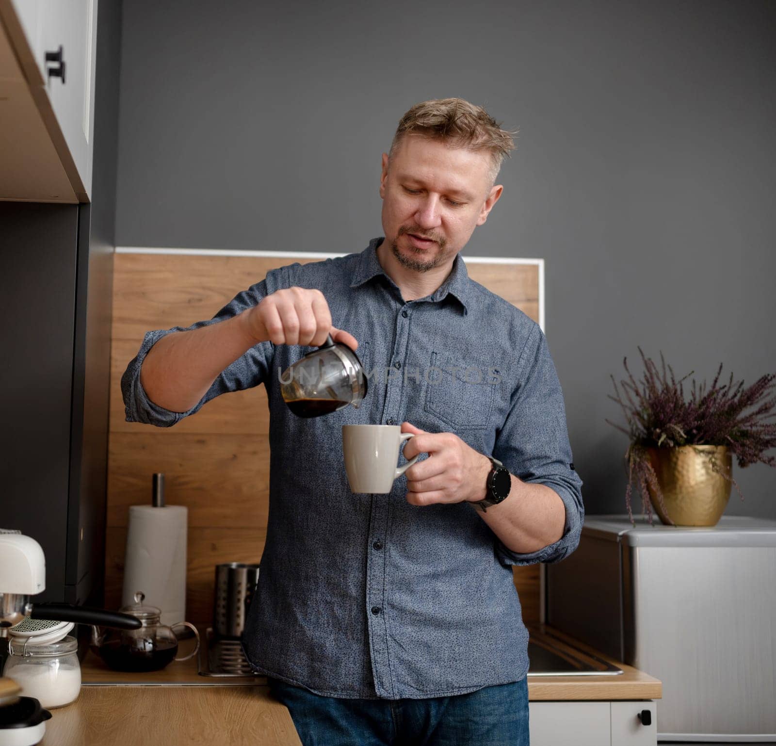 Handsome Man Pouring Himself Coffee At Home In The Kitchen