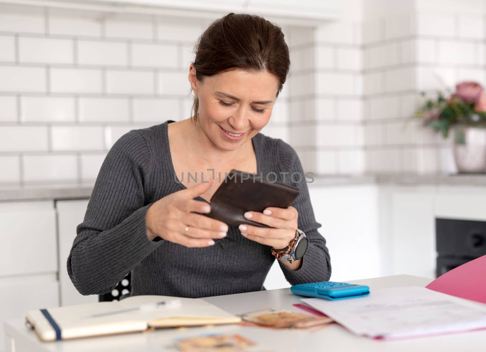 Young Woman Counts Money At Home At Table