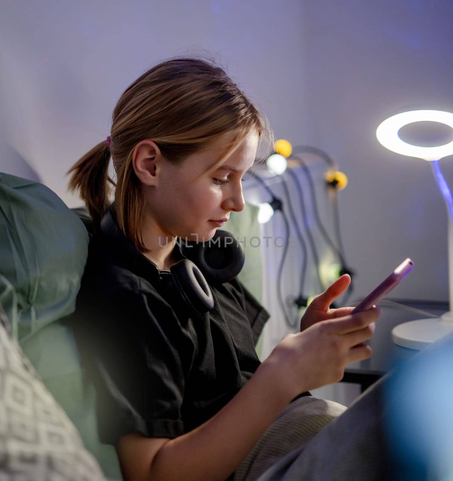 Cute Little Girl Chatting On Social Media With Smartphone In Bed Before Sleep