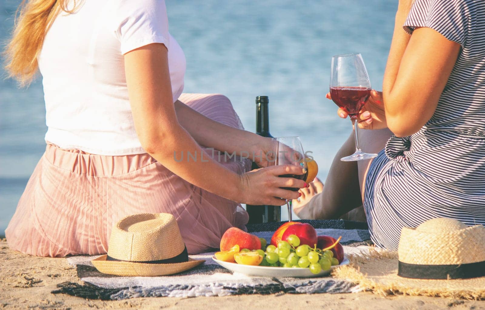 Two girls drinking wine by the sea.