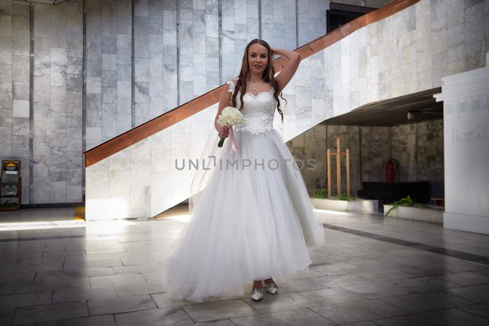 A radiant bride in a stunning gown is elegantly poised at a contemporary venue, showcasing joy and love during her wedding registration.