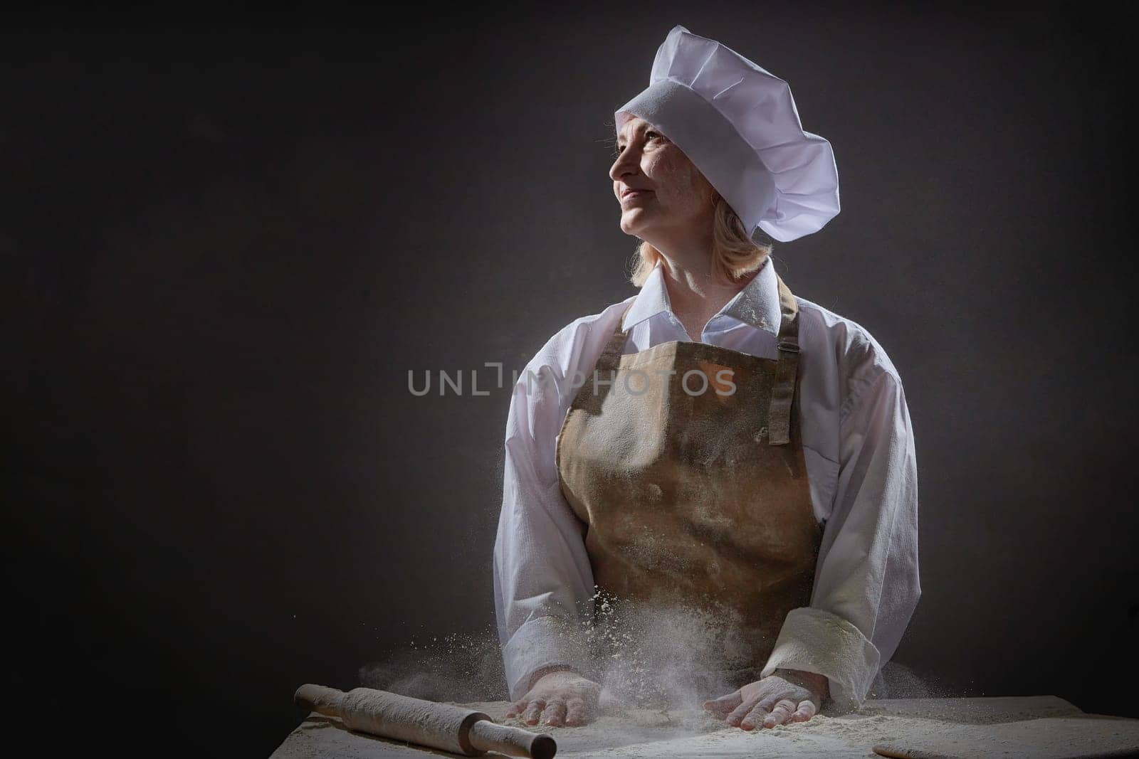 An elderly woman in a chef\'s hat smiles as she joyfully prepares dough from flour, creating a lighthearted atmosphere in the kitchen.