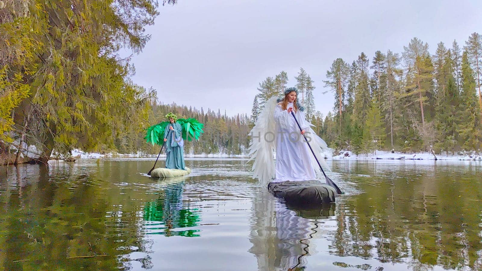 Two girls in flowing dresses explore the serene lake, embodying the magical transition between winter and spring in a captivating role-playing event.