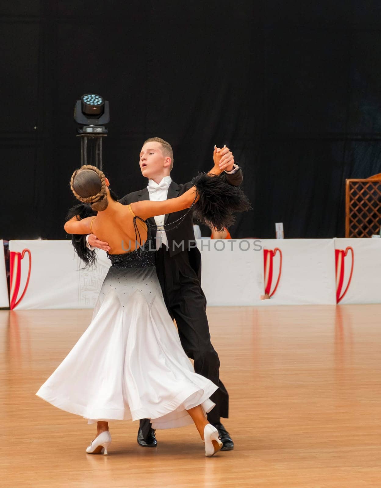 couple dancing standard European program on the dance floor. Young man in tailcoat, girl in black and white long dress and white shoes. Couple dancing waltz, Viennese waltz