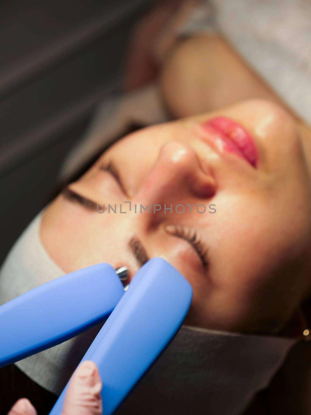 Cosmetic procedure for a woman Microcurrents for a woman's face at a beautician. Rejuvenating effect, toned skin, uniform skin color. Close-up, vertical
