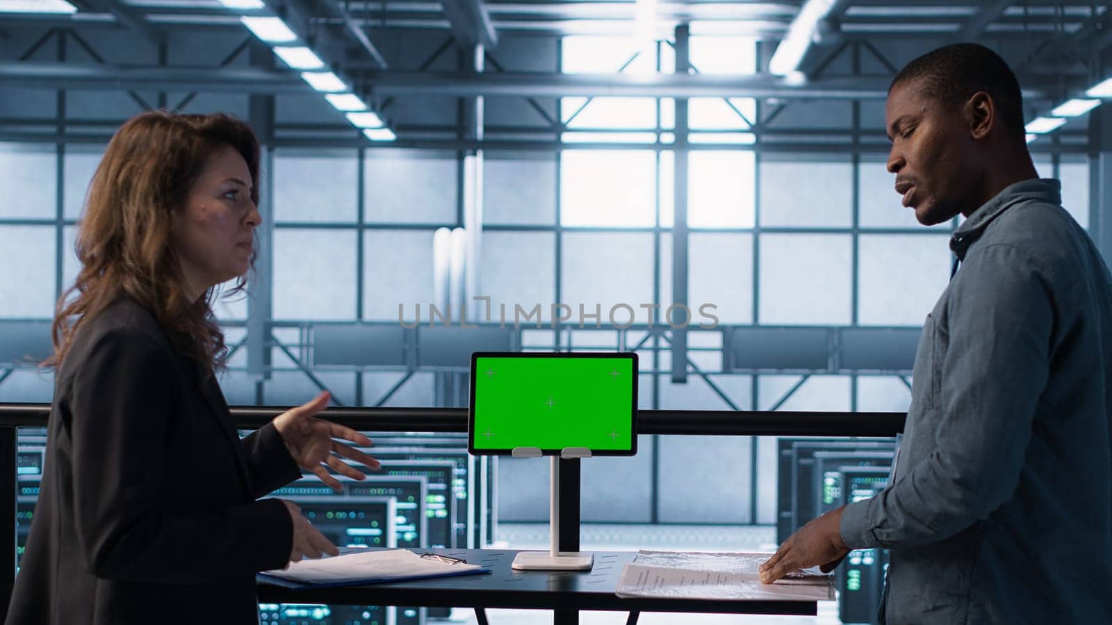 Data center team using mockup green screen tablet, reviewing paperwork files, and security protocols. Server room admins next to chroma key device analyzing critical system reports, camera A