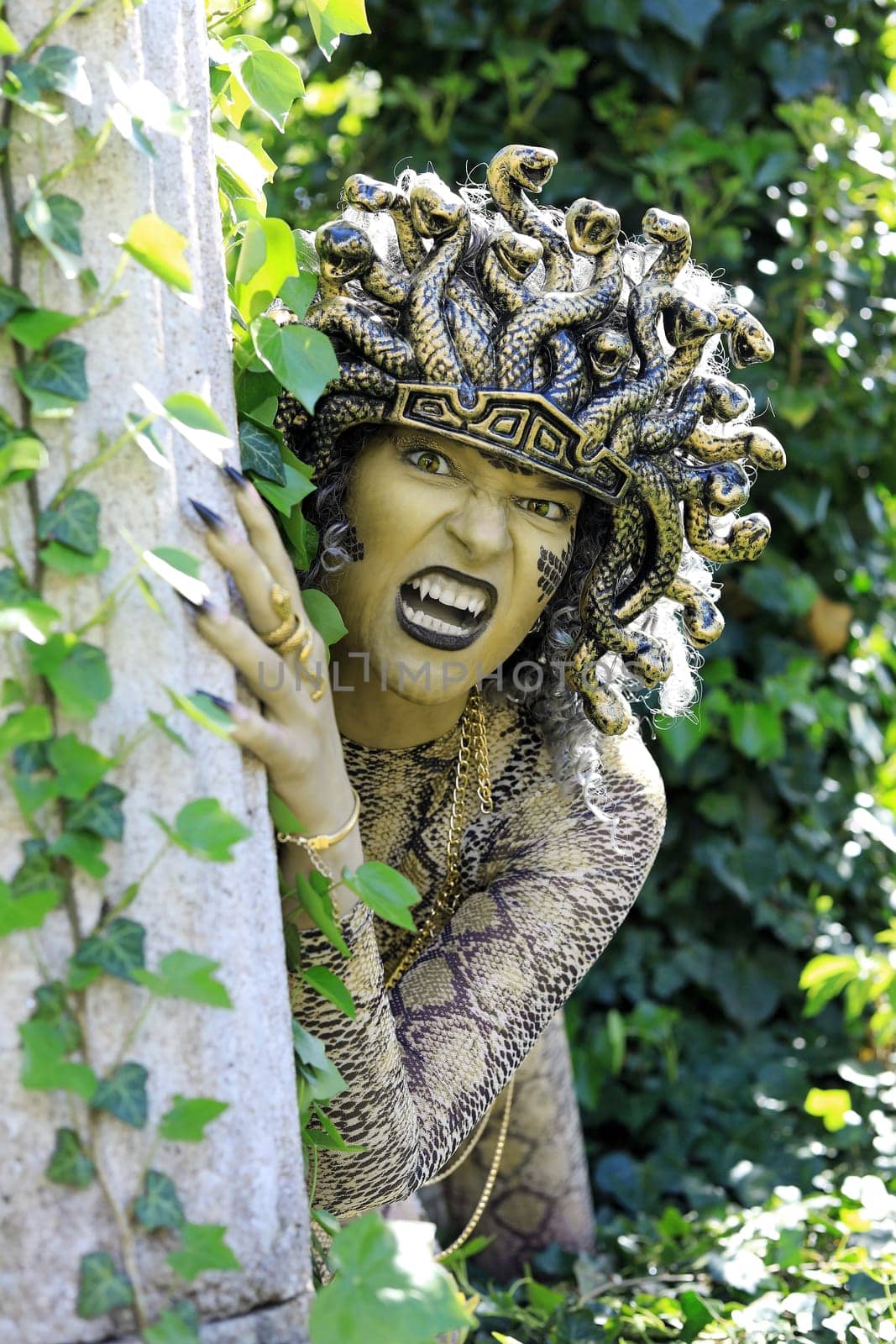 A woman dressed as Medusa with a snake's head and clawed hands