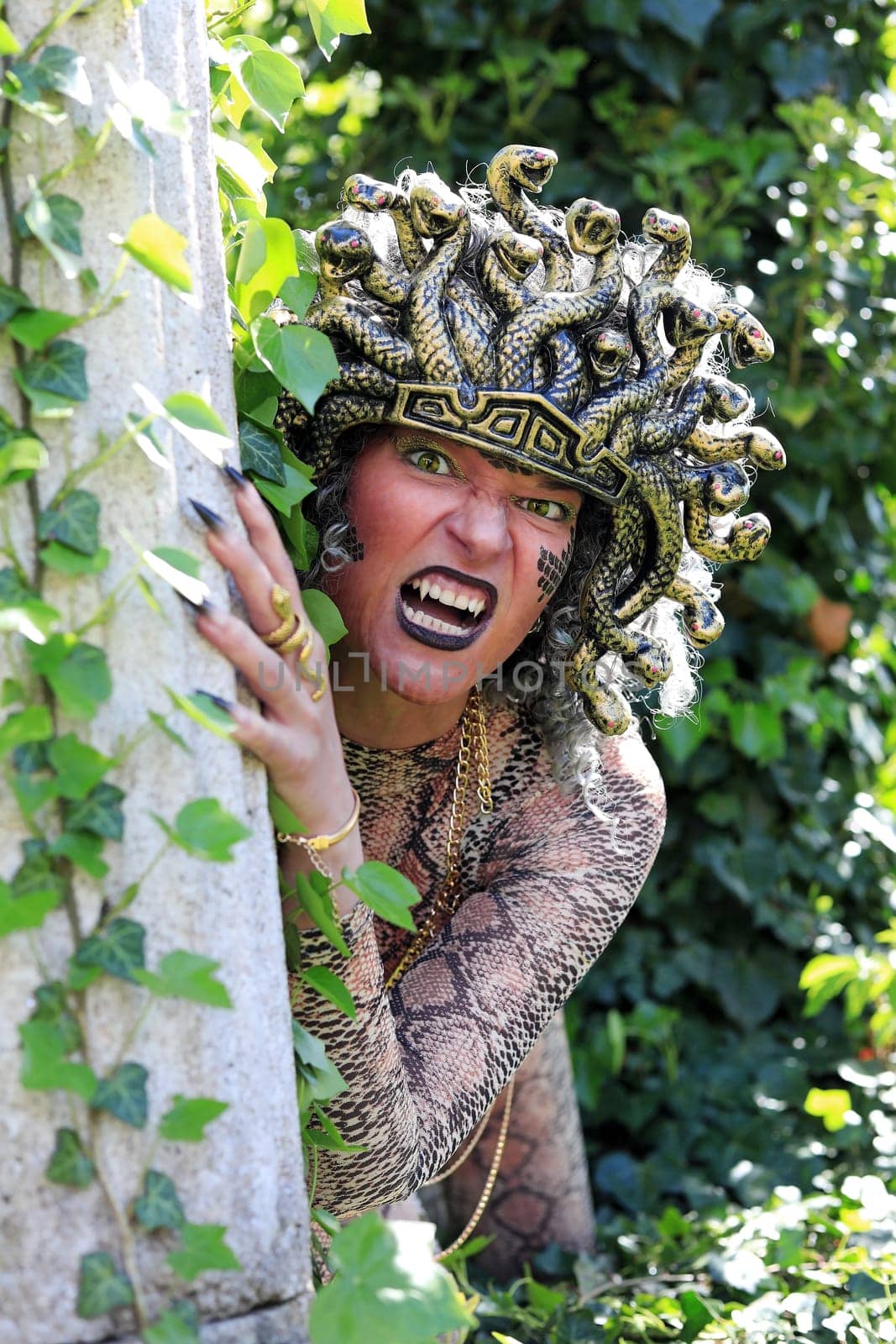 A woman dressed as Medusa with a snake's head and clawed hands
