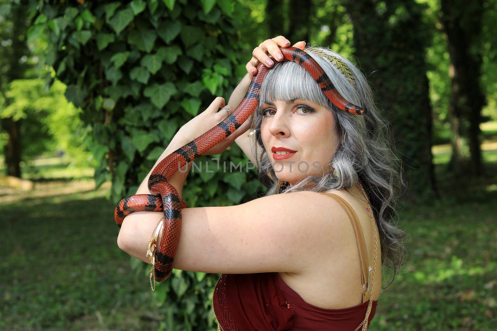 A woman holds a red and black snake over her head