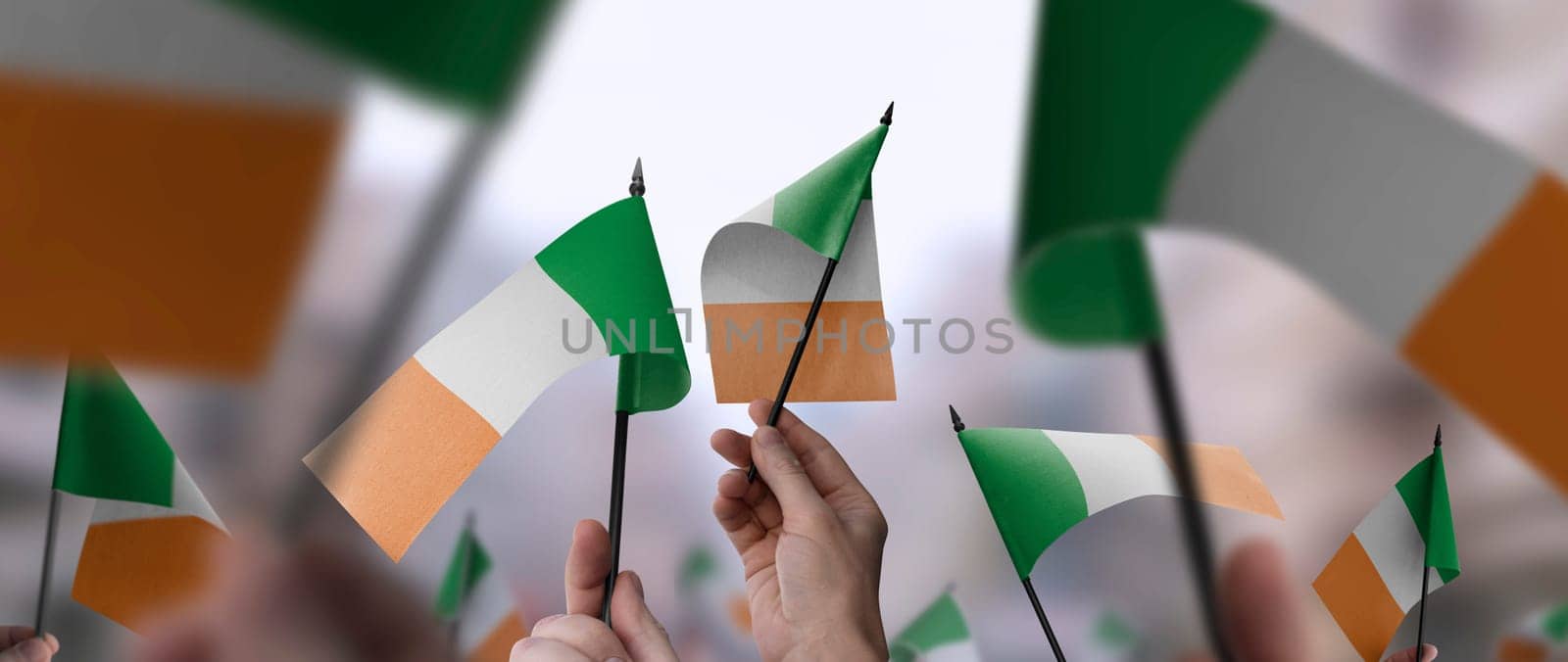 Ireland flags in their hands on a blurred urban background. The photo illustration was created without the use of artificial intelligence, only using Photoshop.