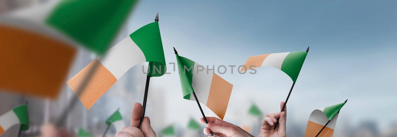 Ireland flags in their hands on a blurred urban background. The photo illustration was created without the use of artificial intelligence, only using Photoshop.